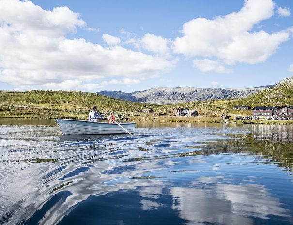 Båt på vannet med fjellstua i bakgrunn