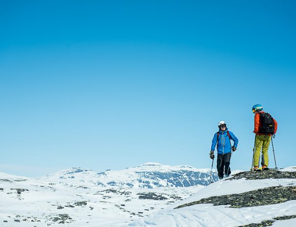 To menn på toppen av alpinbakken en solskinnsdag. Klar for å sette utfor