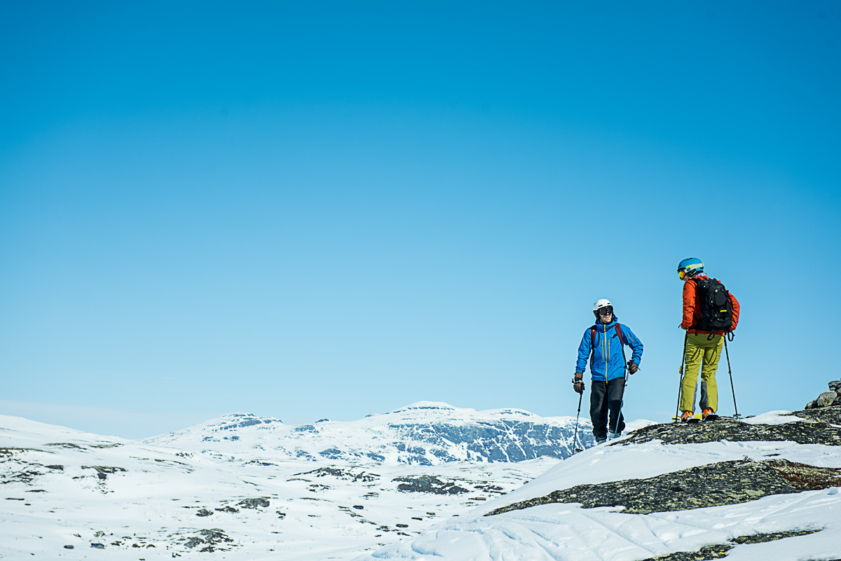 To menn på toppen av alpinbakken en solskinnsdag. Klar for å sette utfor